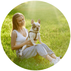 smiling-woman-holding-french-bulldog-grass-1-e1625228907791.png